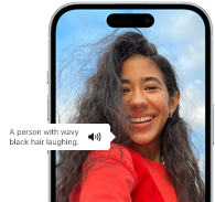 Az iPhone 15-ön a VoiceOver funkció épp elmondja, mi van egy képen: egy hullámos fekete hajú, nevető ember.