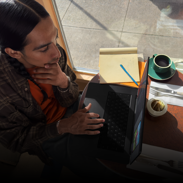 Egy felhasználó akkumulátorról működő MacBook Prón dolgozik egy kávézóban